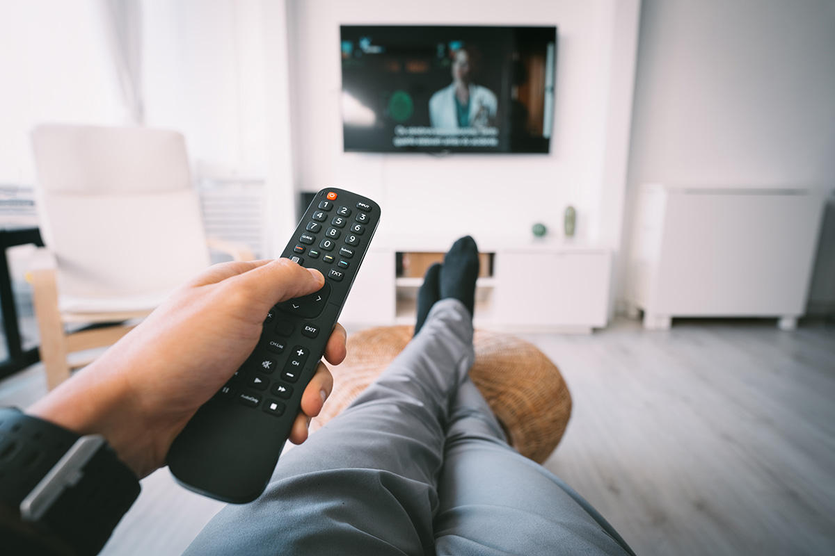 Man sitting on sofa and watching TV with remote controller in his hand. Rest at home. High quality photo